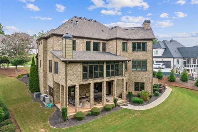 rear view of house with cooling unit, a yard, and a patio