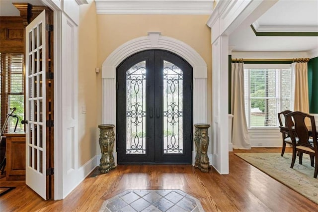 foyer with ornamental molding, hardwood / wood-style flooring, plenty of natural light, and french doors