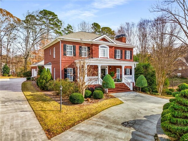 306 Calumet Ln, Monroe, GA 30655 - colonial-style house featuring covered porch, brick siding, a chimney, and driveway