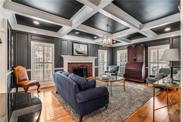 306 Calumet Ln, Monroe, GA 30655 - living area featuring a decorative wall, light wood-style flooring, a brick fireplace, ornamental molding, and a chandelier