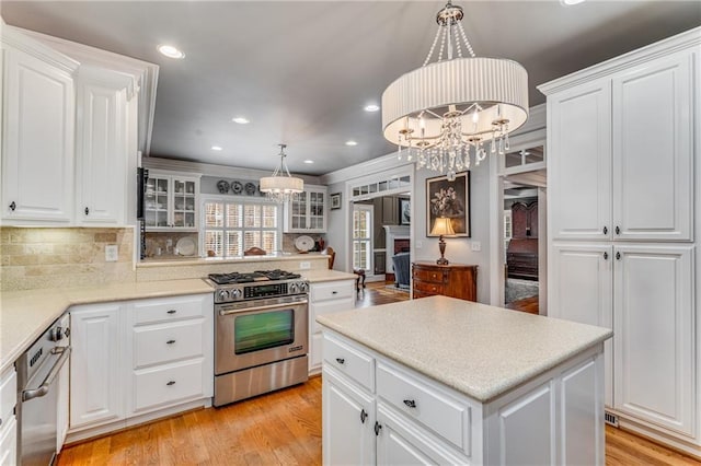 306 Calumet Ln, Monroe, GA 30655 - kitchen with stainless steel gas stove, a chandelier, white cabinetry, decorative backsplash, and recessed lighting