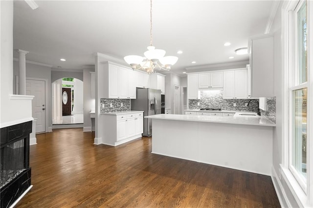 kitchen featuring a sink, gas stovetop, a chandelier, arched walkways, and stainless steel fridge with ice dispenser