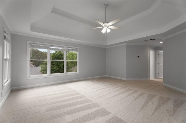 spare room featuring a ceiling fan, a raised ceiling, light carpet, and ornamental molding