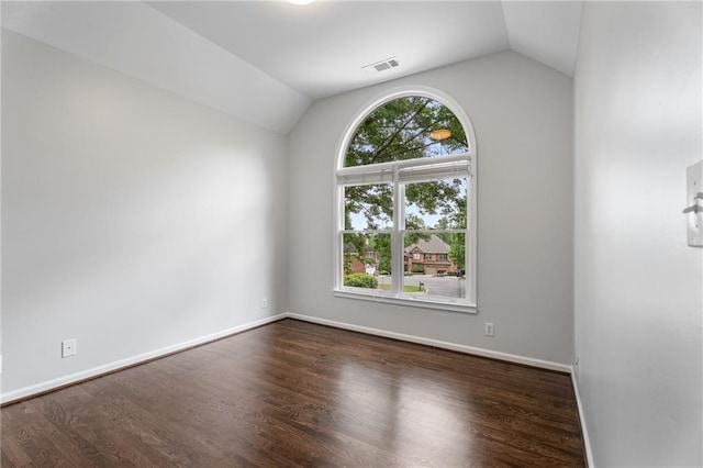 unfurnished room with lofted ceiling, visible vents, dark wood finished floors, and baseboards