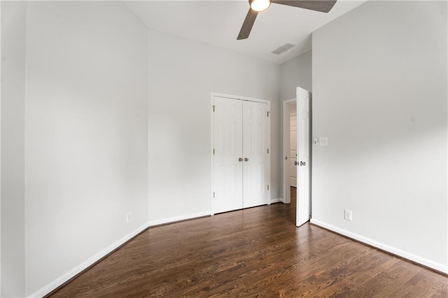 unfurnished bedroom with lofted ceiling, a closet, baseboards, wood finished floors, and a ceiling fan