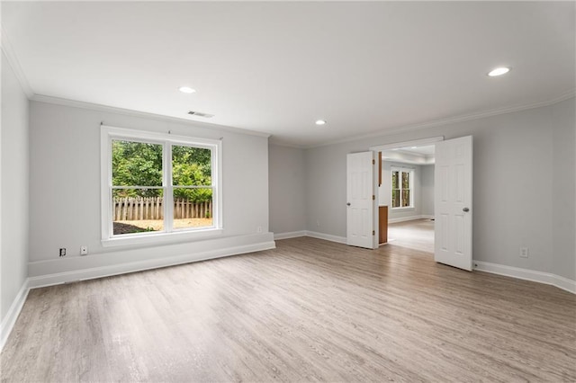 empty room with crown molding, light wood finished floors, visible vents, and a wealth of natural light
