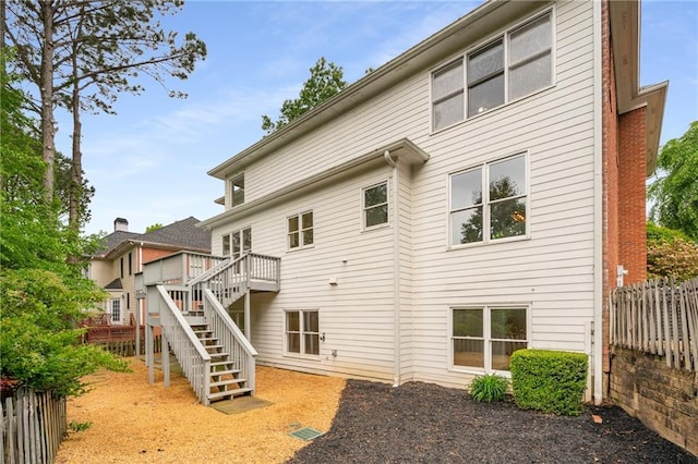 back of property with fence, stairs, and a wooden deck