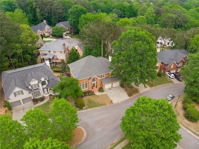 drone / aerial view featuring a wooded view and a residential view