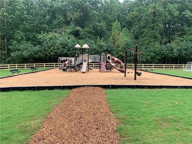 community playground featuring a yard, a forest view, and fence