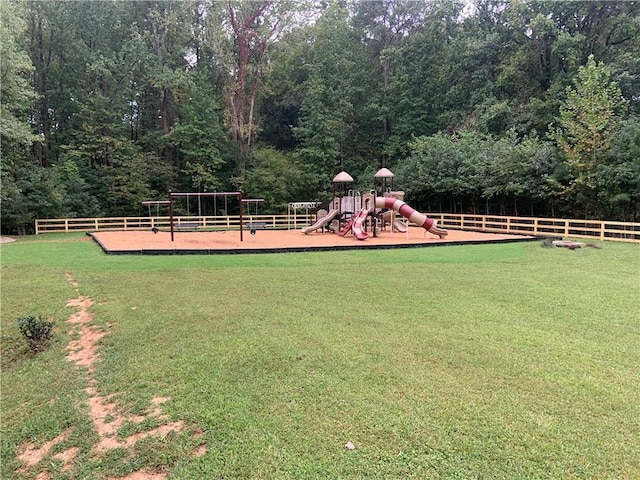 view of yard with fence, playground community, and a forest view