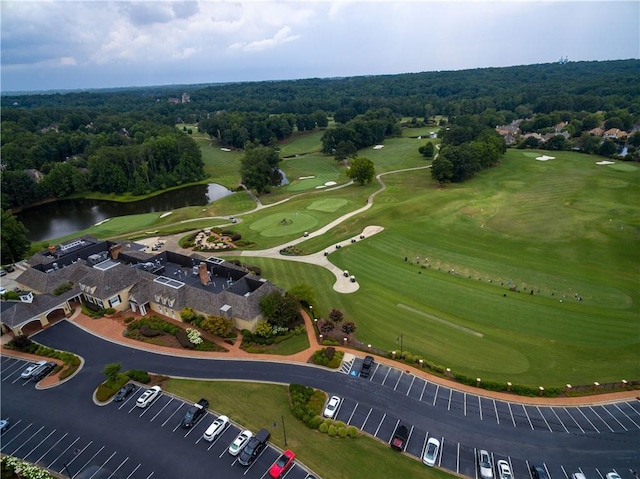 drone / aerial view with golf course view, a water view, and a view of trees