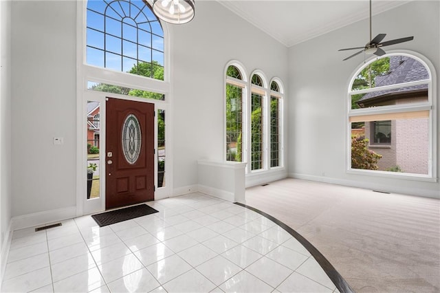foyer with ornamental molding, a towering ceiling, visible vents, and baseboards