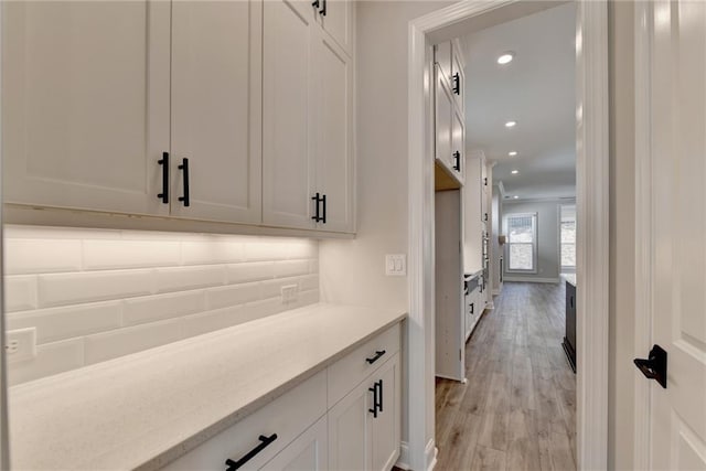 bar featuring light stone countertops, light hardwood / wood-style flooring, and white cabinetry