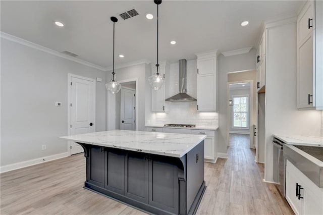 kitchen featuring pendant lighting, light hardwood / wood-style flooring, wall chimney range hood, white cabinetry, and a spacious island