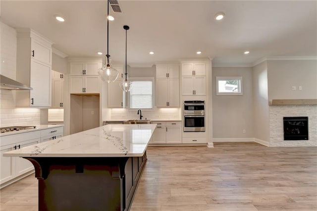 kitchen with double oven, a wealth of natural light, a center island, and light hardwood / wood-style floors