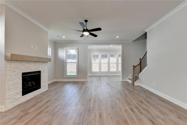 unfurnished living room with ceiling fan, light wood-type flooring, crown molding, and a fireplace