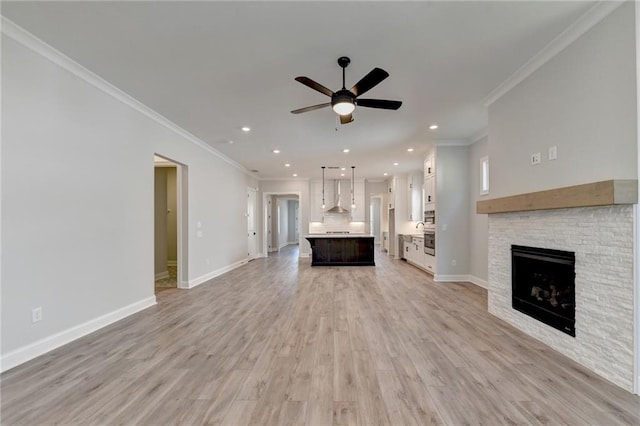 unfurnished living room featuring ceiling fan, a fireplace, crown molding, and light hardwood / wood-style floors