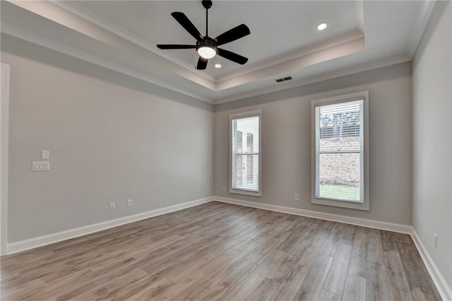 spare room with crown molding, ceiling fan, light hardwood / wood-style floors, and a raised ceiling