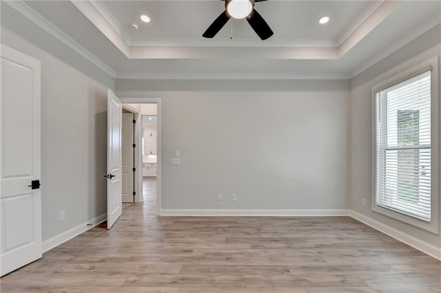 spare room with a raised ceiling, ornamental molding, light wood-type flooring, and ceiling fan