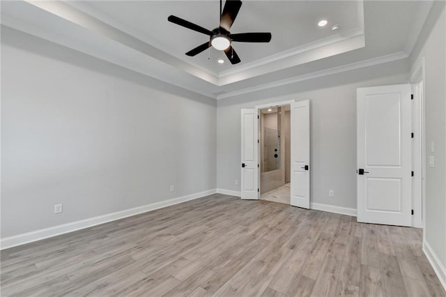 unfurnished bedroom featuring crown molding, a tray ceiling, light wood-type flooring, and ceiling fan