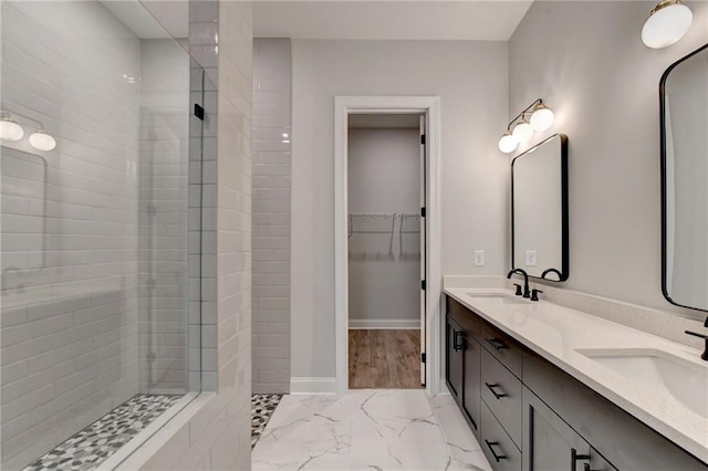 bathroom with tiled shower and vanity