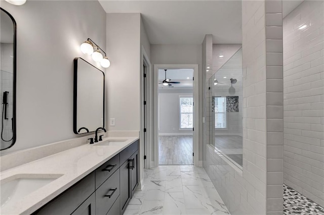 bathroom with ceiling fan, vanity, a tile shower, and wood-type flooring