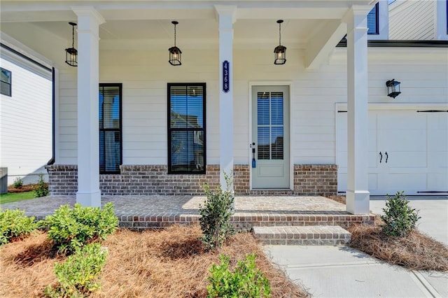 view of exterior entry featuring a porch and a garage