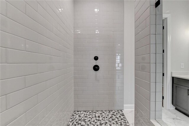 bathroom with tiled shower and vanity