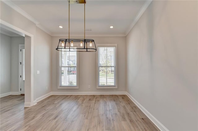 unfurnished dining area with a notable chandelier, light wood-type flooring, and crown molding