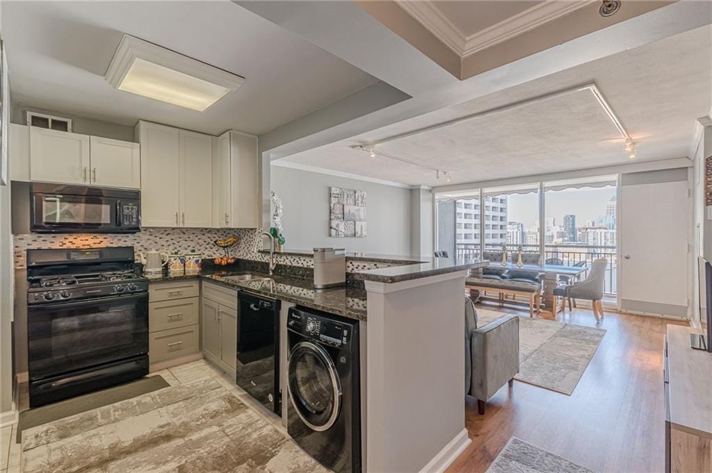 kitchen with rail lighting, black appliances, sink, and washer / dryer