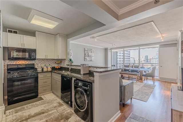 kitchen with rail lighting, black appliances, sink, and washer / dryer