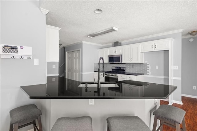 93 Pebble Creek Dr, Newnan, GA 30265 - kitchen with stainless steel appliances, dark countertops, ornamental molding, white cabinets, and a textured ceiling