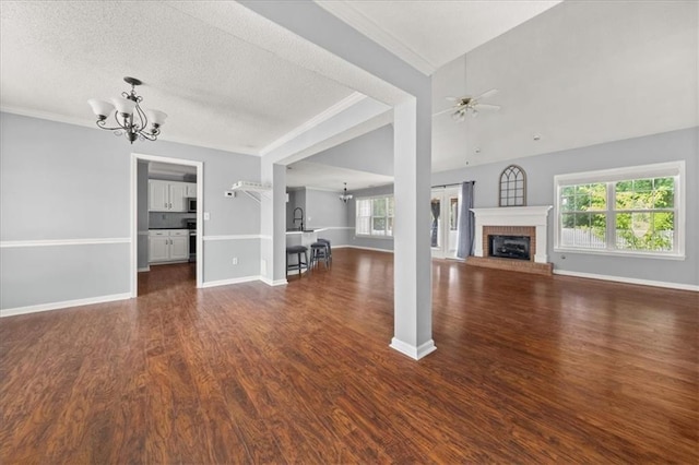93 Pebble Creek Dr, Newnan, GA 30265 - unfurnished living room with a chandelier, dark wood-style floors, a brick fireplace, crown molding, and a textured ceiling