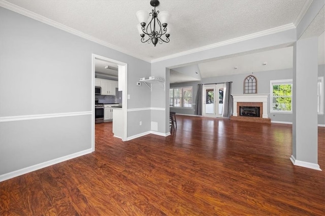 93 Pebble Creek Dr, Newnan, GA 30265 - unfurnished living room featuring a chandelier, dark wood finished floors, a textured ceiling, crown molding, and a fireplace