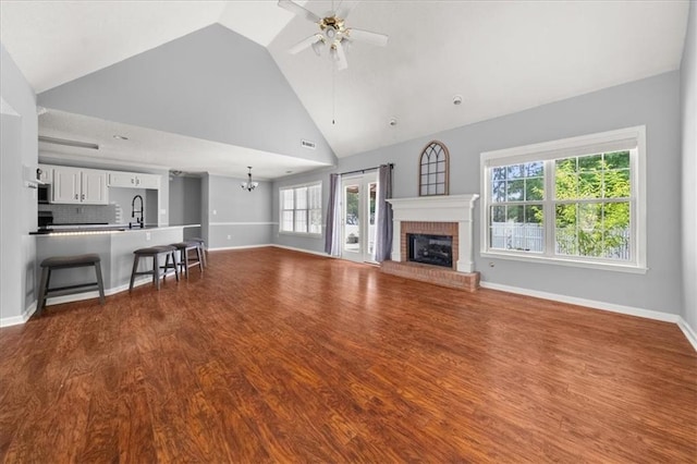 93 Pebble Creek Dr, Newnan, GA 30265 - unfurnished living room featuring ceiling fan, a brick fireplace, plenty of natural light, dark wood finished floors, and high vaulted ceiling