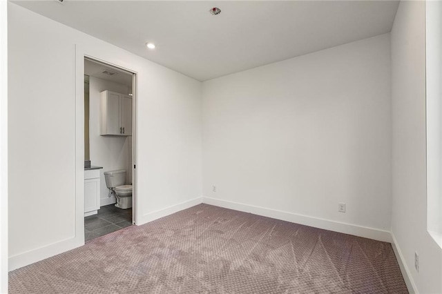 unfurnished bedroom with dark carpet and connected bathroom