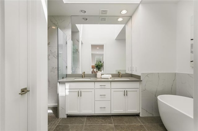 bathroom featuring tile patterned floors, vanity, a tub to relax in, and tile walls