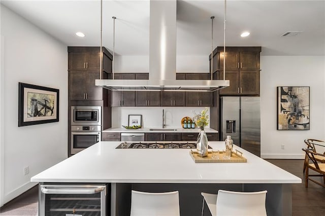 kitchen featuring an island with sink, beverage cooler, and range hood