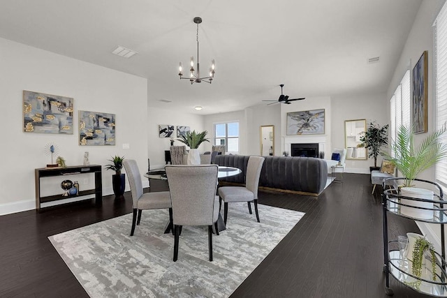 dining room with ceiling fan with notable chandelier and dark hardwood / wood-style flooring