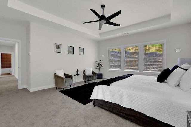 carpeted bedroom with ceiling fan and a raised ceiling