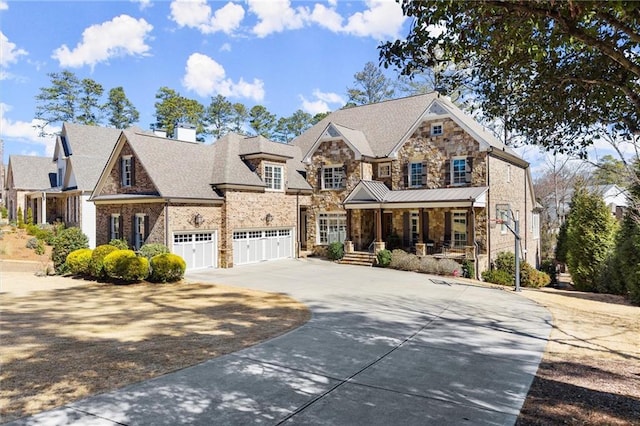 view of front facade with a chimney, covered porch, an attached garage, stone siding, and driveway