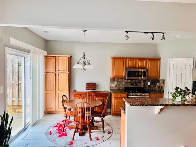 kitchen with pendant lighting, backsplash, track lighting, light tile patterned flooring, and stainless steel appliances