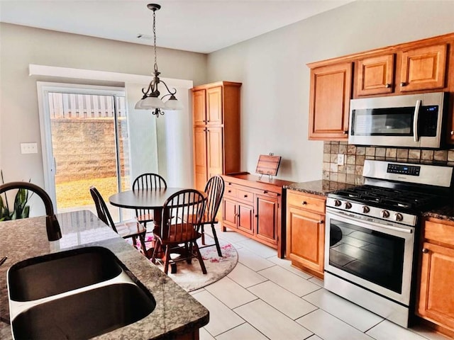 kitchen featuring sink, decorative light fixtures, tasteful backsplash, dark stone counters, and stainless steel appliances