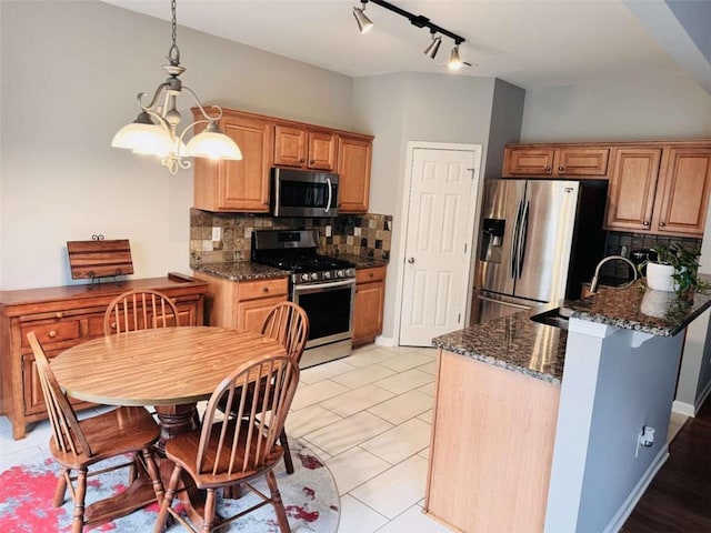 kitchen with appliances with stainless steel finishes, sink, tasteful backsplash, light tile patterned floors, and dark stone counters