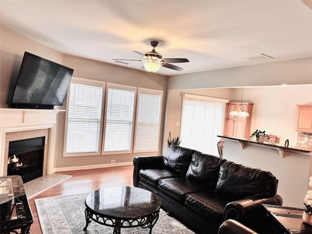 living room featuring ceiling fan, light hardwood / wood-style flooring, and a fireplace