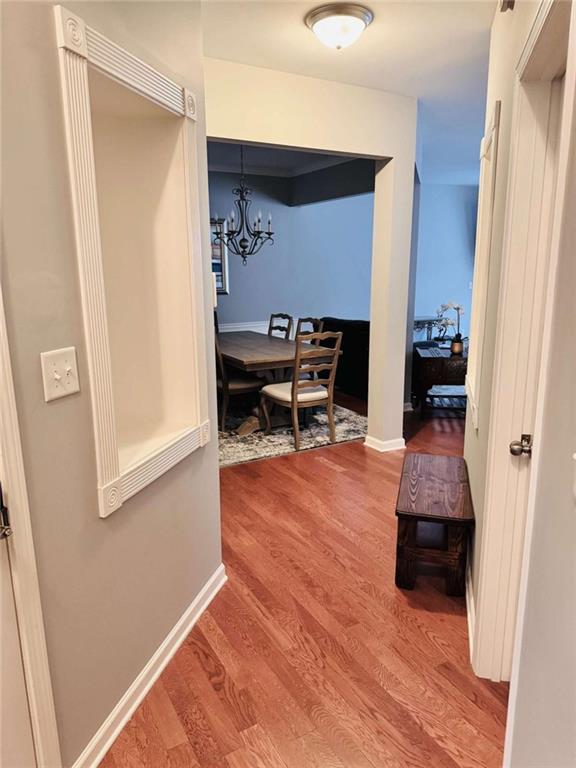 corridor with hardwood / wood-style flooring and a chandelier