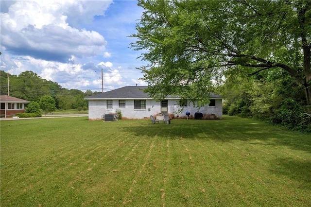 rear view of house featuring a lawn and central AC