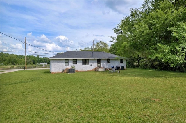 rear view of property featuring central AC unit and a yard