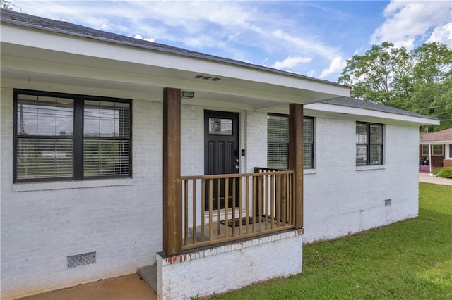 property entrance featuring brick siding, crawl space, and a lawn