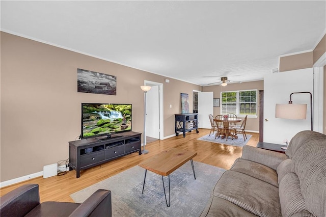 living area with baseboards, ceiling fan, and wood finished floors